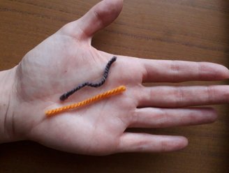 Palm holding two pieces of string, orange and black. On click the image leads you to projects webpage.